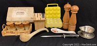 Assorted kitchen items including vintage wooden relish crate with ceramic jars, wooden cutter block, wooden ladle, ceramic spoon rest, metal cutter sharpener, stainless steel gravy boat, and tall wooden salt and pepper grinders.