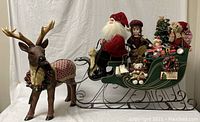 Wide photo of the large decorative Christmas scene showing Santa, sleigh, reindeer, and toys within the sleigh.