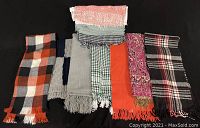Photo showing the full lot of 10 scarves in various colors and patterns laid flat on a black surface.