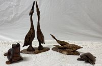 All four carved wooden animal figures shown together on a white crochet fabric background: two tall birds on a shared base, one smaller bird, one seal, and one turtle.