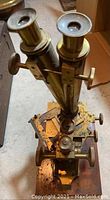 Top view of the antique brass binocular microscope showing dual eyepieces and adjustment knobs.