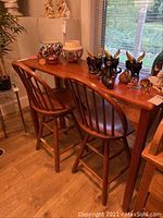 Bar table and stools with wooden finish and decorative items on table top.