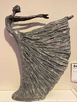 Full view of the dancing woman figurine showing the flowing skirt and outstretched arms.