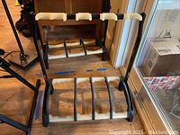 Black Konig & Meyer guitar stand showing entire unit with upper part for guitar necks and lower part with slots for guitar bodies with foam padding.