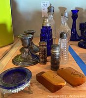 Photo showing various salt and pepper shakers, cobalt salt dish, and Gorham candle holders on wooden surface