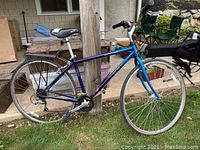 Side view of blue Trek MultiTrack 720 bicycle showing frame, rear rack, seat, and water bottle holder