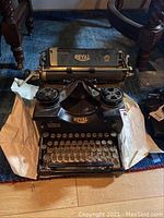 Top front view of the vintage Royal manual typewriter placed on paper on a floor, showing keyboard and ribbon spools.