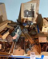 Photo showing assortment of microscope lenses, containers, metal rods, and an old photo/manual.