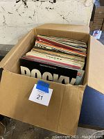 View into a large cardboard box filled with over 65 vinyl records, showing a variety of albums.