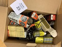 Top-down view of a cardboard box containing a mix of electron tubes, some in their original diverse branded boxes and others loose, with a paper note included.