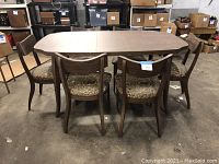 Full dining set with table and 6 chairs set up in warehouse environment