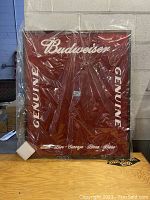Front view of Budweiser dart board background in protective plastic wrapping showing branding and size.