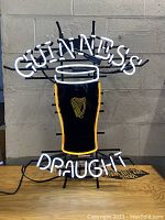 Guinness Draught neon light with yellow outline on harp logo shown lit and unlit.