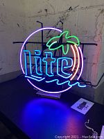 Front view of the illuminated Miller Lite neon sign showing colorful neon tubing shaped with palm tree and text 'lite'.