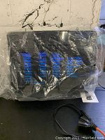 Two double sided Miller Lite neon signs wrapped in plastic and placed on table near a white wall.