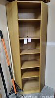 Front view of the oak veneer corner bookcase showing all six shelves inside with adjustable slots.