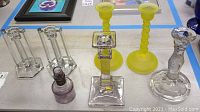 Photo of the entire lot showing all candlesticks and perfume bottle in various colors and styles including yellow holders.
