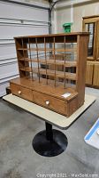Front three-quarter view of wooden letter sorter on table showing cubby grid and drawers.