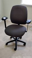 Front view of the black fabric office chair showing padded seat and backrest, armrests, and caster legs