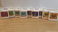 Front view of 10 one-liter bottles of Growers Paradise nutrient solutions placed side by side on a wooden surface.