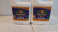 Close-up of two 1-liter Ganja Bloom hydroponic nutrient containers labeled 6-0-3 and 1-4-8.