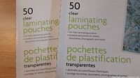 Boxes of Grand & Toy laminating pouches in two sizes, 50 pouches each, total 100 sheets.