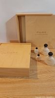 Two wooden keepsake boxes labeled 'Pure Alfred Sung' and four Alfred Sung Pure perfume bottles behind them.
