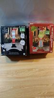 Two boxed inflatable lawn balloons in original packaging featuring Jack Skellington dressed as Santa and the Grinch character, shown from front.