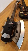 Close-up of the Gene Simmons Axe guitar controller showing its unique axe-shaped body with signature and decals.