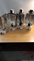 Four fixtures lined up on a table showing reflectors and ballasts.