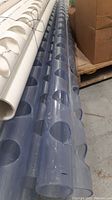 Side view showing multiple clear PVC pipes with drilled circular holes, bundled together.