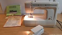 Complete front view of Kenmore 12 sewing machine with manual and foot pedal.