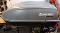 Side view of SportRack Explorer rooftop cargo case showing gray molded plastic with logo