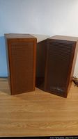 Pair of vintage Telefunken stereo speakers in wooden cabinets with slatted front panels on a hardwood floor.