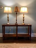 Full frontal view of wood couch table with three lamps on top showing overall shape and design