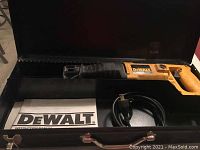 DeWalt reciprocating saw in metal case with power cord and owner's manual visible inside the case