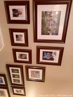 Photo showing multiple wood picture frames with matting and placeholder pictures, hung on a wall.
