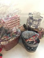 Six assorted basket containers including wicker and metal types with some decorative wrapping and stuffing viewed from the front.