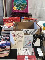 Box containing assorted greeting cards and several health and fitness books in stacks. Two signed running books visible. Some cards on display on and in box.