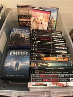 Photo of DVDs stacked and arranged in a plastic bin showing various TV series and movies.