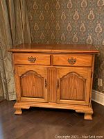 Front view of the Thomasville pecan wood server showing two drawers with brass handles and two doors with decorative panels and brass vertical pulls.
