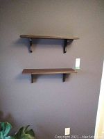 Two wooden wall shelves mounted on a gray wall.
