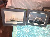 Two framed prints on the floor, showing sailing ships with metal frames, matting, and glass, each measuring 20x26 inches