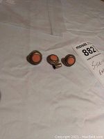 Image of sterling silver pendant and earrings with coral colored stones displayed on a white cloth