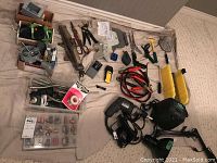 Various tools including pliers, wire cutters, soldering supplies, jumper cables, hand tools, small lights on carpet.