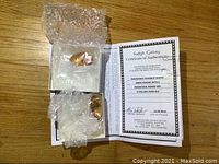 Two amber pendants wrapped in bubble wrap atop a certificate of authenticity