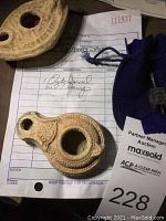 Two terra-cotta oil lamps on top of original purchase receipt and auction tag
