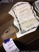 Earthenware oil lamp alongside certificate of authenticity