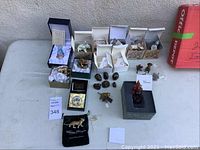 Full lot arrangement on table, showing boxes of trinket boxes, porcelain cats, bronze figures and glass Ganesh
