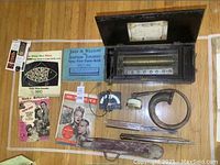 Overview of all lot items laid out on floor: music box, horn, stands, sheet music, meter, leather tube
